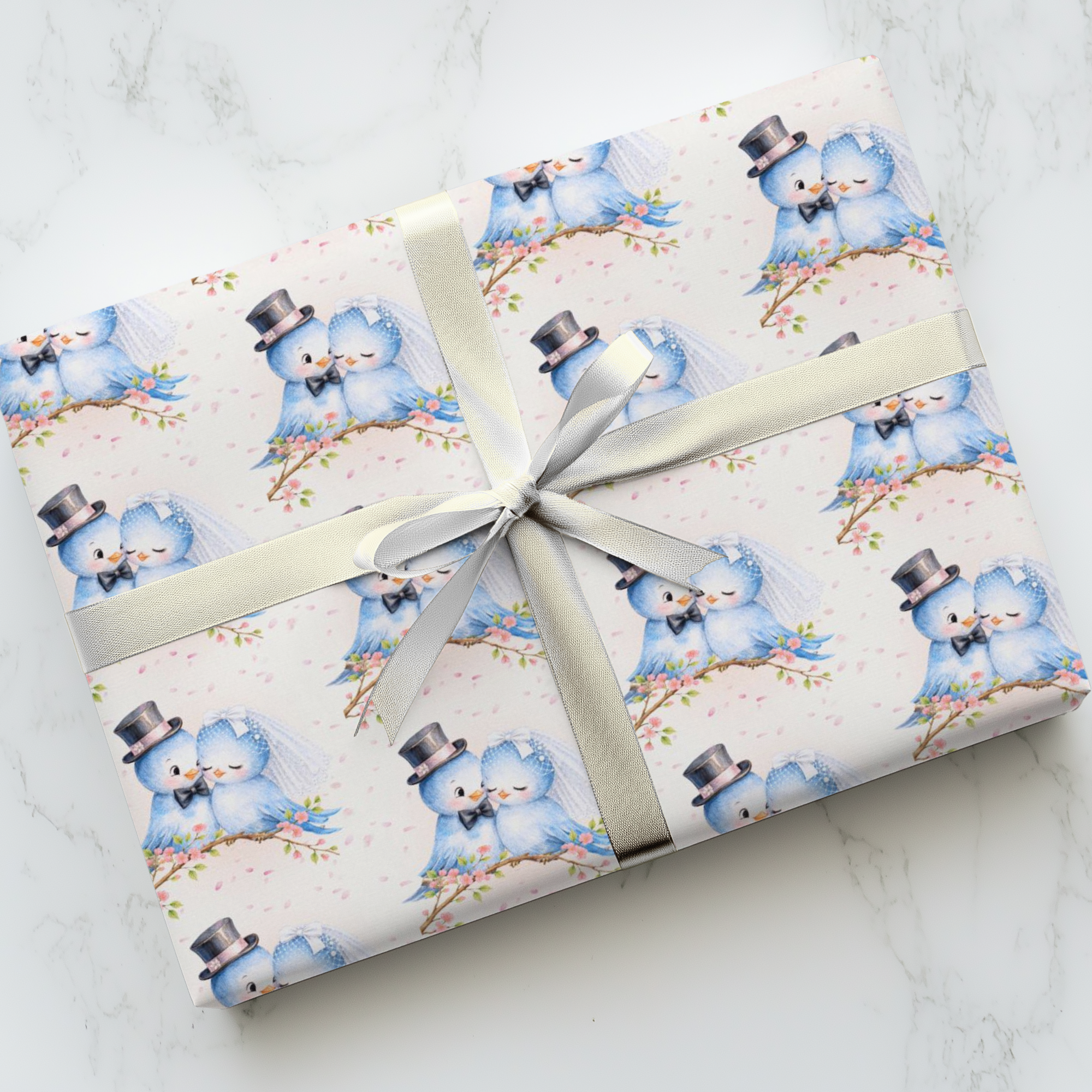 Wedding gift wrapped in romantic bluebird bride and groom with a silver ribbon on a marble surface.