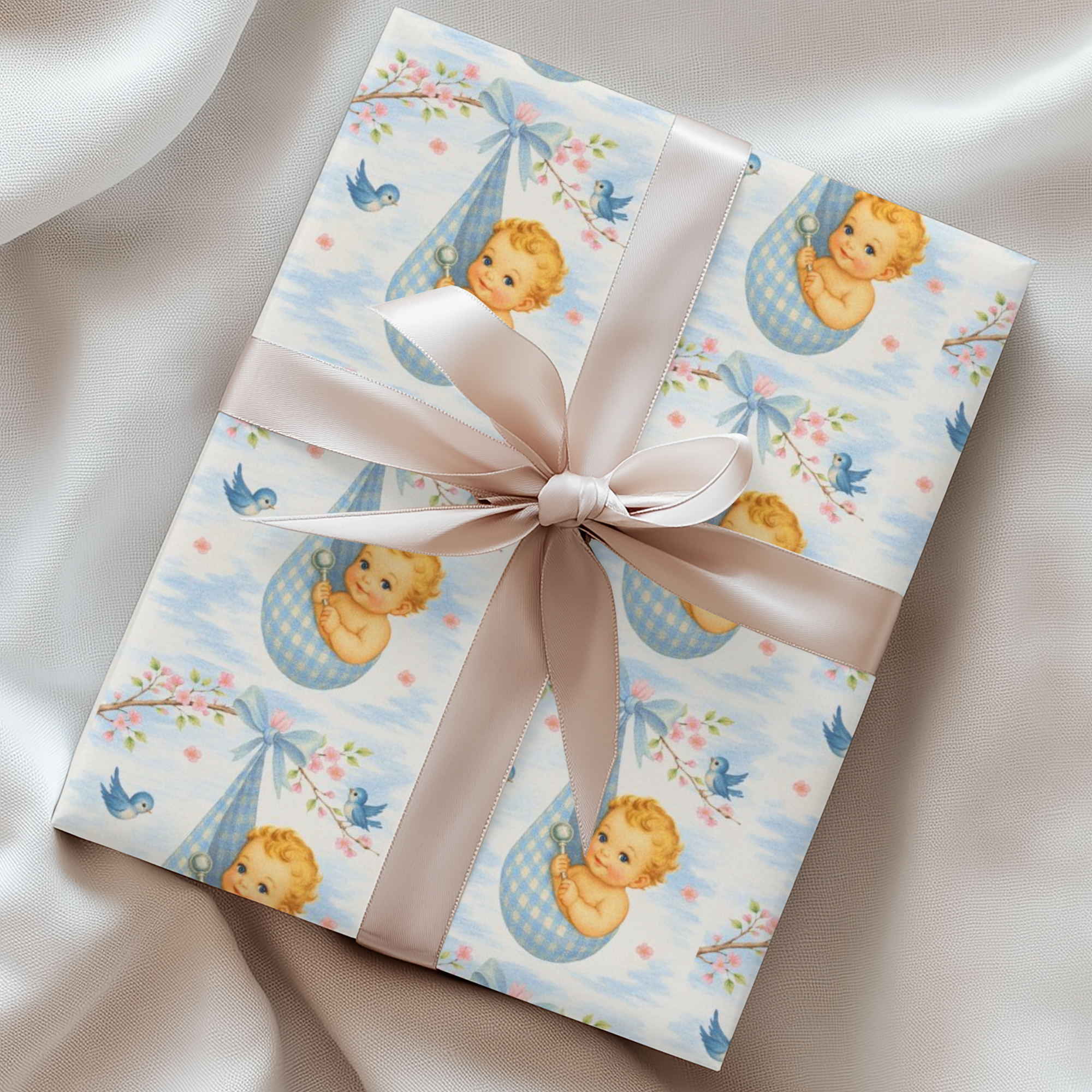 Gift box wrapped in baby and cherry blossom paper with a bow on a soft fabric background