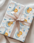 Gift box wrapped in baby and cherry blossom paper with a bow on a soft fabric background