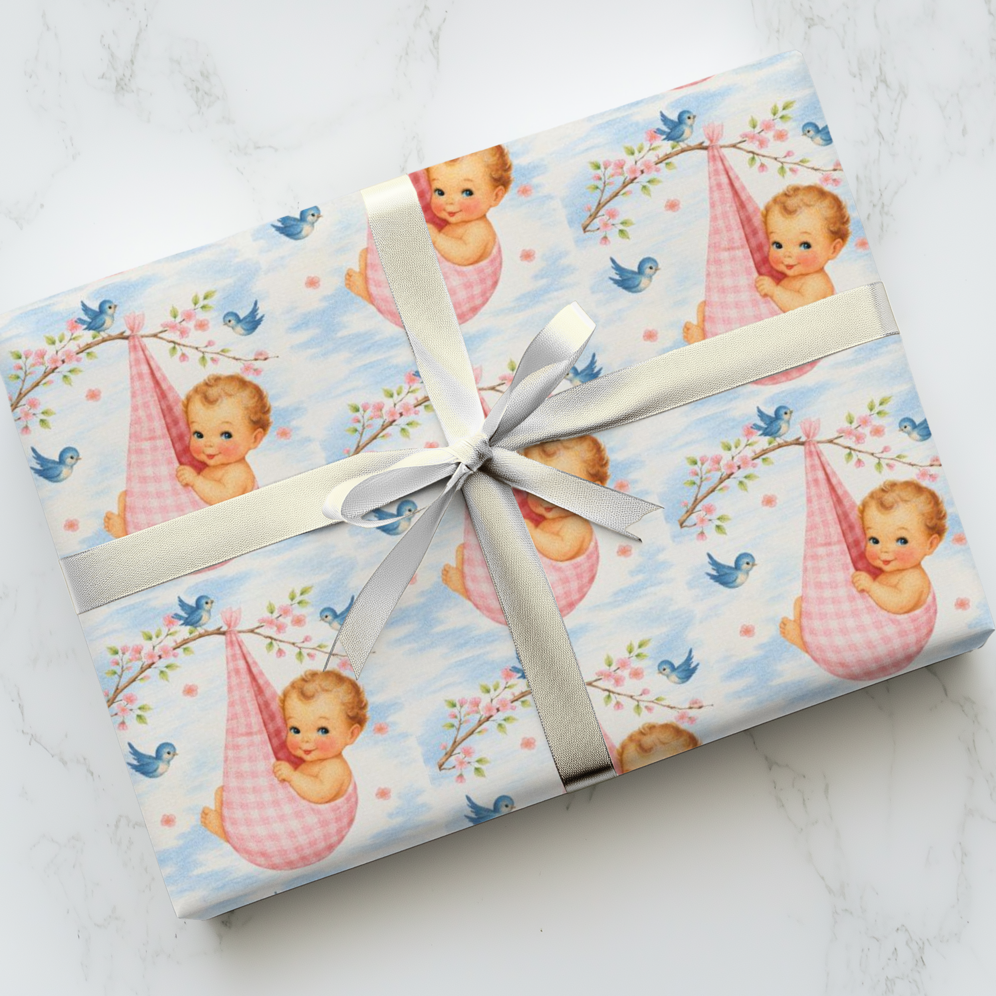 Gift wrapped in baby and cherry blossom designed paper with a ribbon on a marble surface