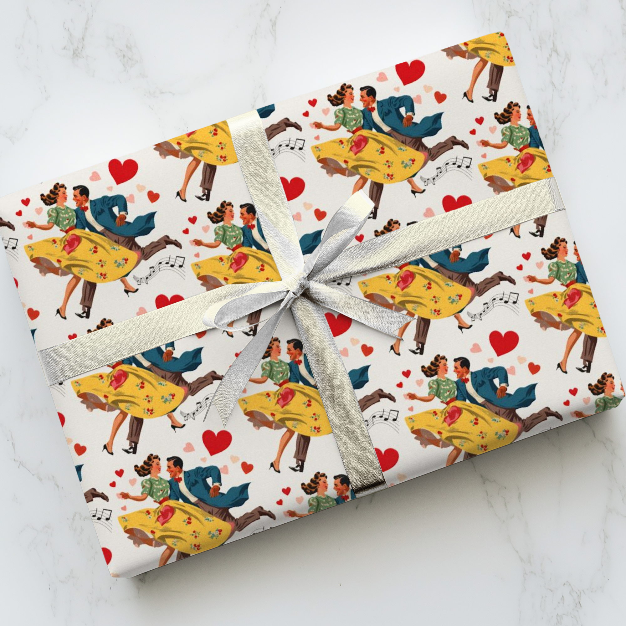 Gift wrapped in colorful wrapping paper with dancing couples, musical notes and hearts on a white marble surface.