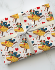 Gift wrapped in colorful wrapping paper with dancing couples, musical notes and hearts on a white marble surface.