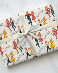 Gift wrapped in retro-themed paper with dancing couples and music notes on a white marble surface.