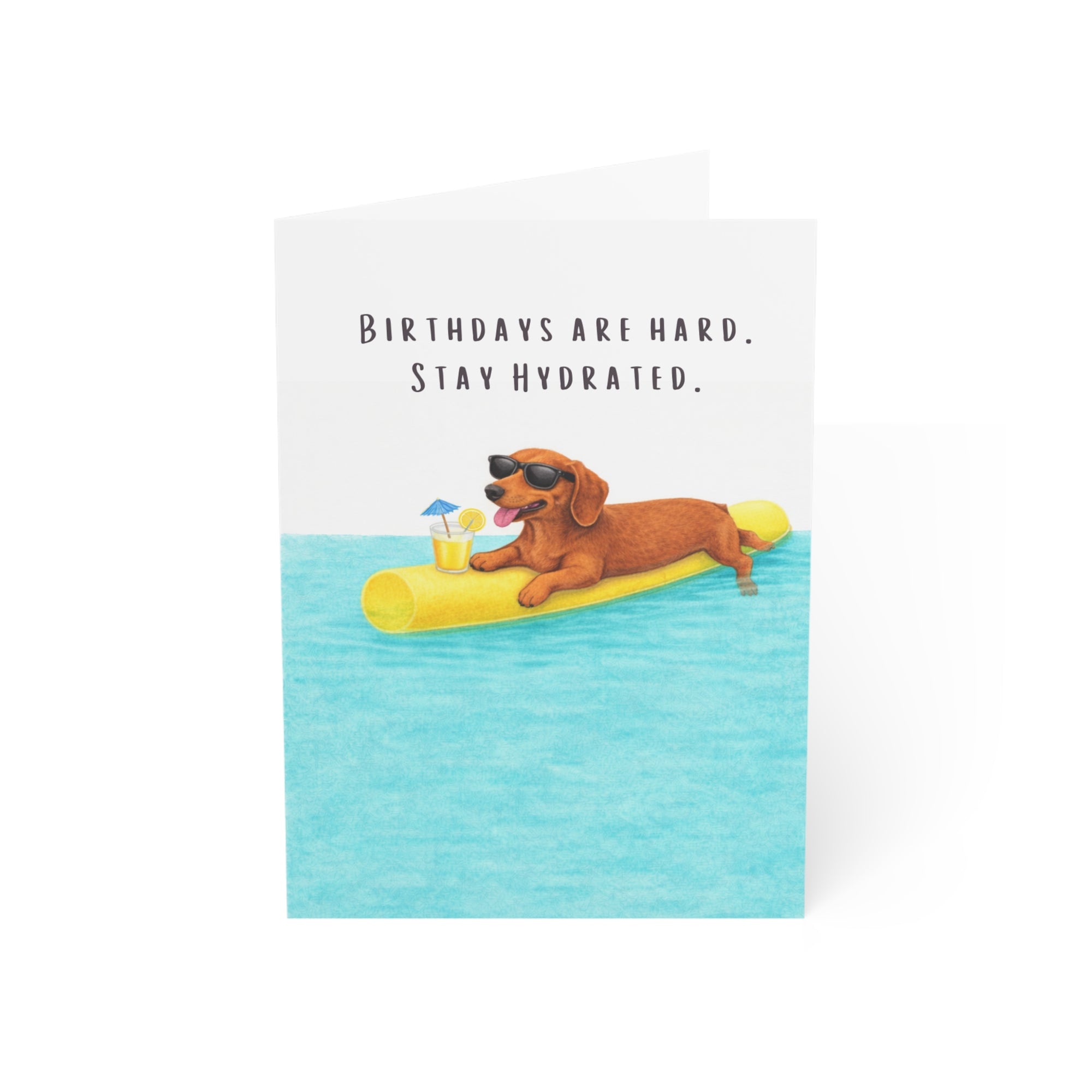Birthday card with a doxie on a pool noodle in water, text 'Birthdays are hard. Stay Hydrated.'