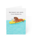 Birthday card with a doxie on a pool noodle in water, text 'Birthdays are hard. Stay Hydrated.'