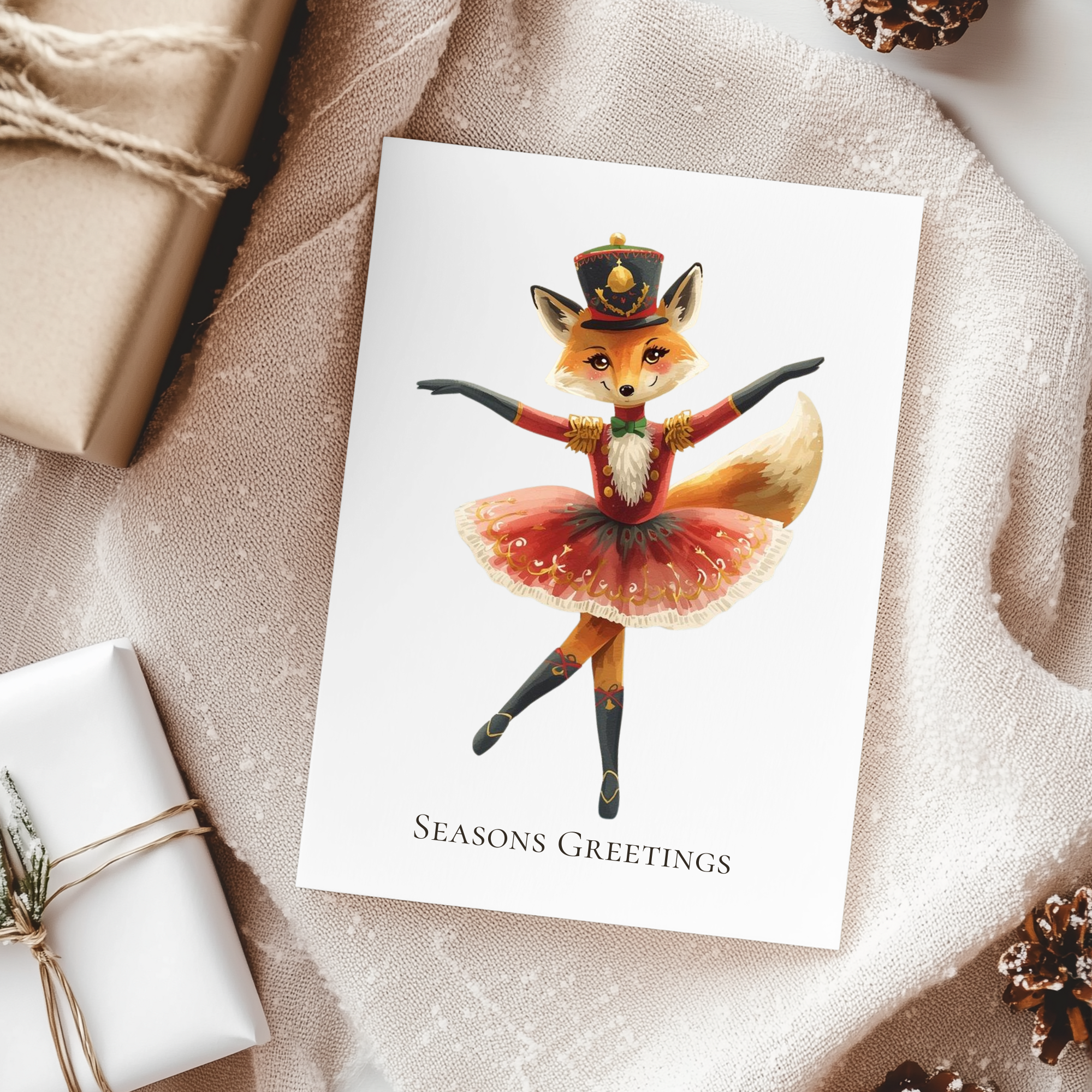 Greeting card with a fox character in a ballet outfit on a textured surface with gift wraps and pine cones.