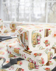 Gift box wrapped in floral and cake-themed paper with scissors on a matching tablecloth.