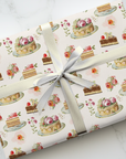 Gift wrapped in paper with cake pattern on a marble surface.