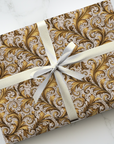 Gift box with gold and gray pattern and white ribbon on a marble surface
