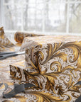 Decorative gold and gray patterned wrapping paper with scissors on a light background