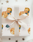 Gift box with a ribbon and baby-themed wrapping paper featuring illustrations of babies and stars.