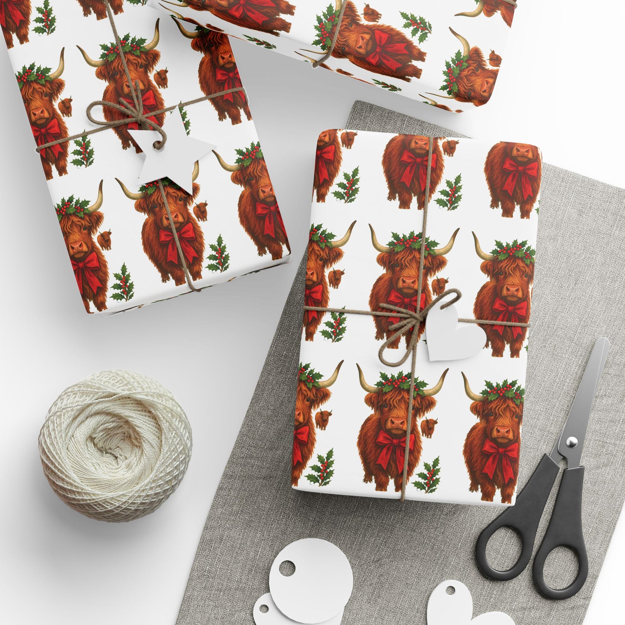 Gift wrap with Highland cow pattern on a white surface with scissors and yarn.