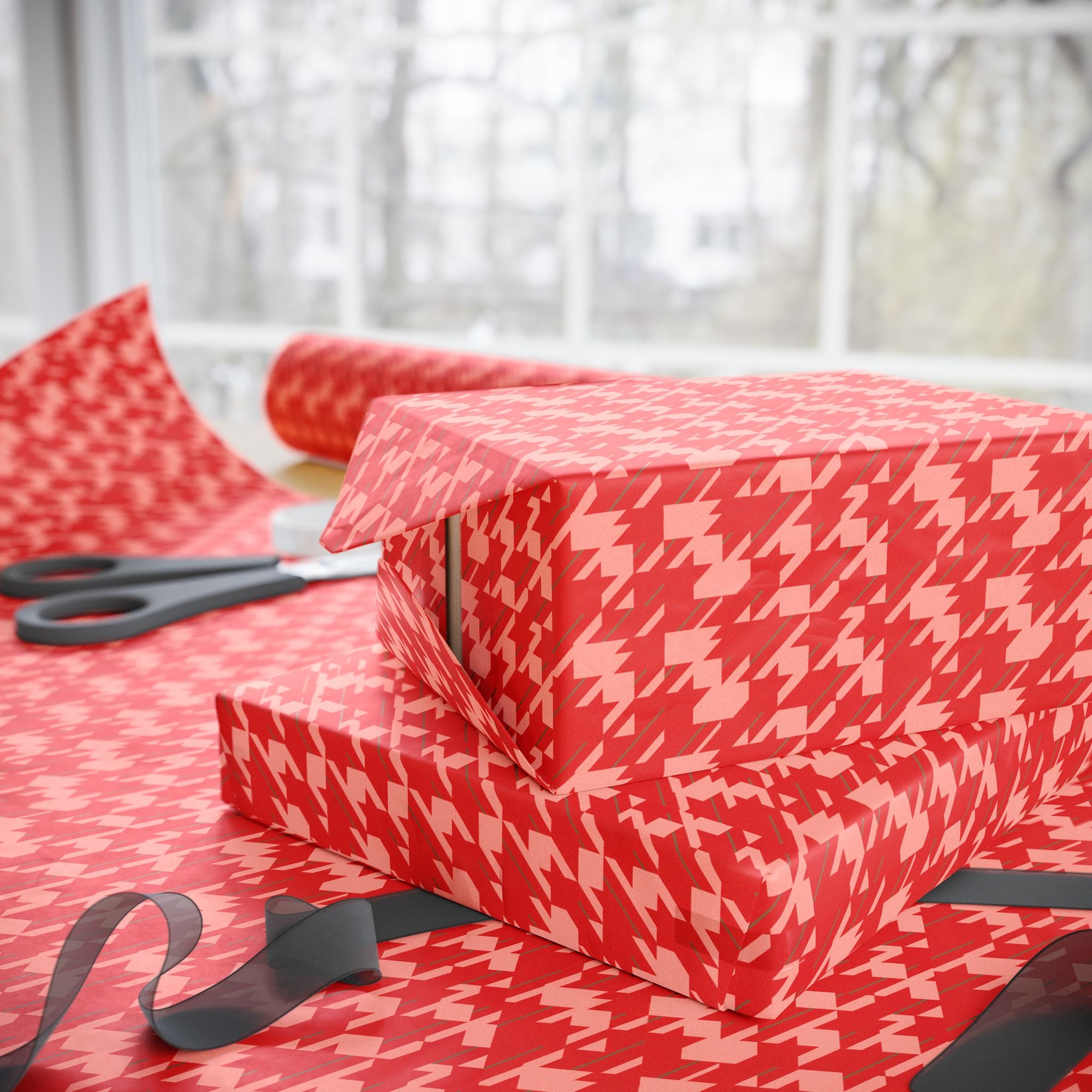 Gift wrapped in red houndstooth pattern with scissors on a matching surface.