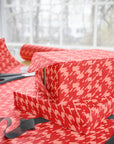 Gift wrapped in red houndstooth pattern with scissors on a matching surface.