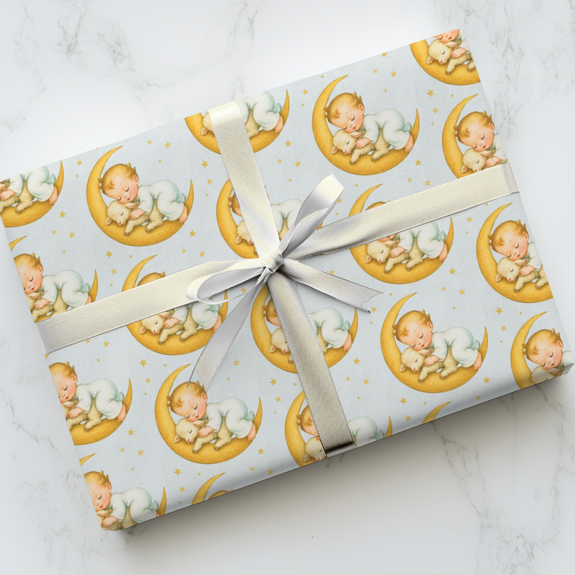 Gift wrapped in patterned paper with a baby on a moon design, tied with a ribbon on a marble surface.