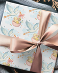 Gift wrapped in paper with stork and baby design, tied with a pink ribbon on a textured surface.