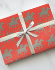 Red wrapping paper featuring silver polo players in a horse and rider pattern.