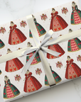 Gift wrapped in paper with queen of hearts themed design on a white surface