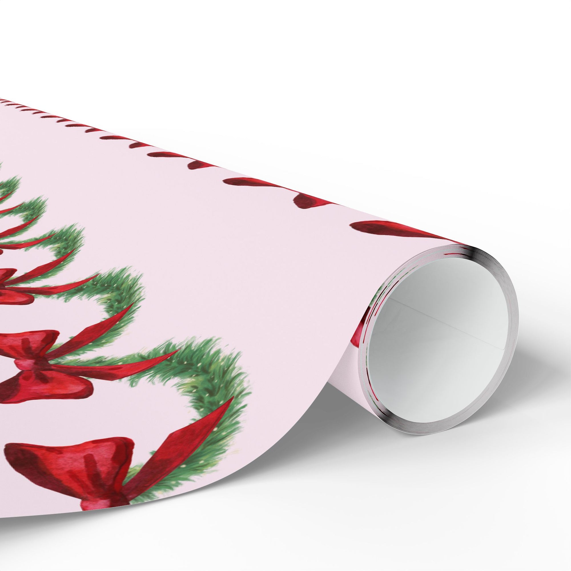Roll of Christmas-themed wrapping paper with red bows and green garland on a pink background