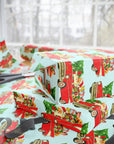 Retro Santa driving a red classic Chevy with presents Christmas wrapping paper on a light turquoise background.