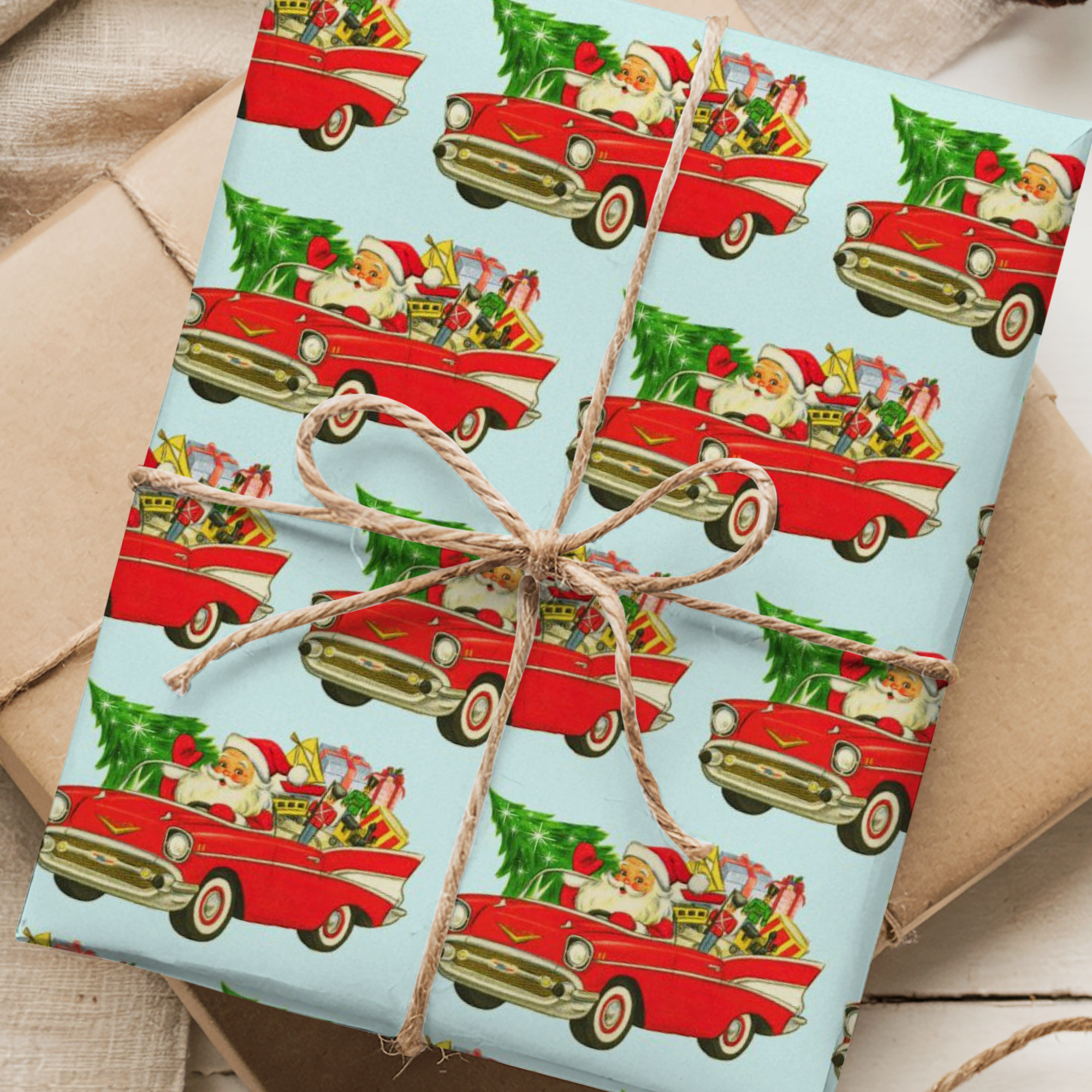 Christmas gift wrap on a light aqua background featuing santa driving a classic 1957 Chevy.