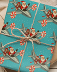 Retro christmas wrappinug paper featuring santa flying peppermint turboprop plane with gifts on a turquoise snowy background.