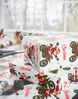 Christmas wrapping paper featuring Santa on a dirt bike doing tricks on a white background.