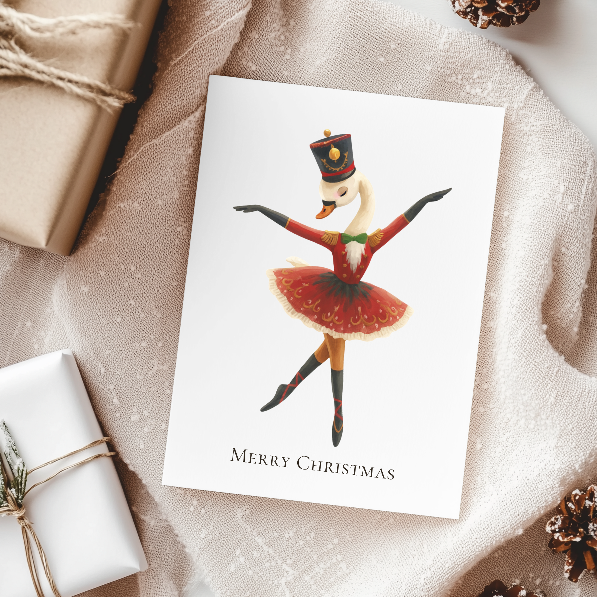 Christmas card with a swan dancer design on a textured surface with gift wraps and pine cones.