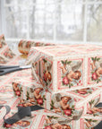 Boxes wrapped in vintage-style Valentine's Day postage stamp wrapping paper with cherubs and flowers on a table.