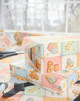 Close up of vintage baby quilt wrapping paper showing patchwork squares with teddy bears stars and rocking horses.