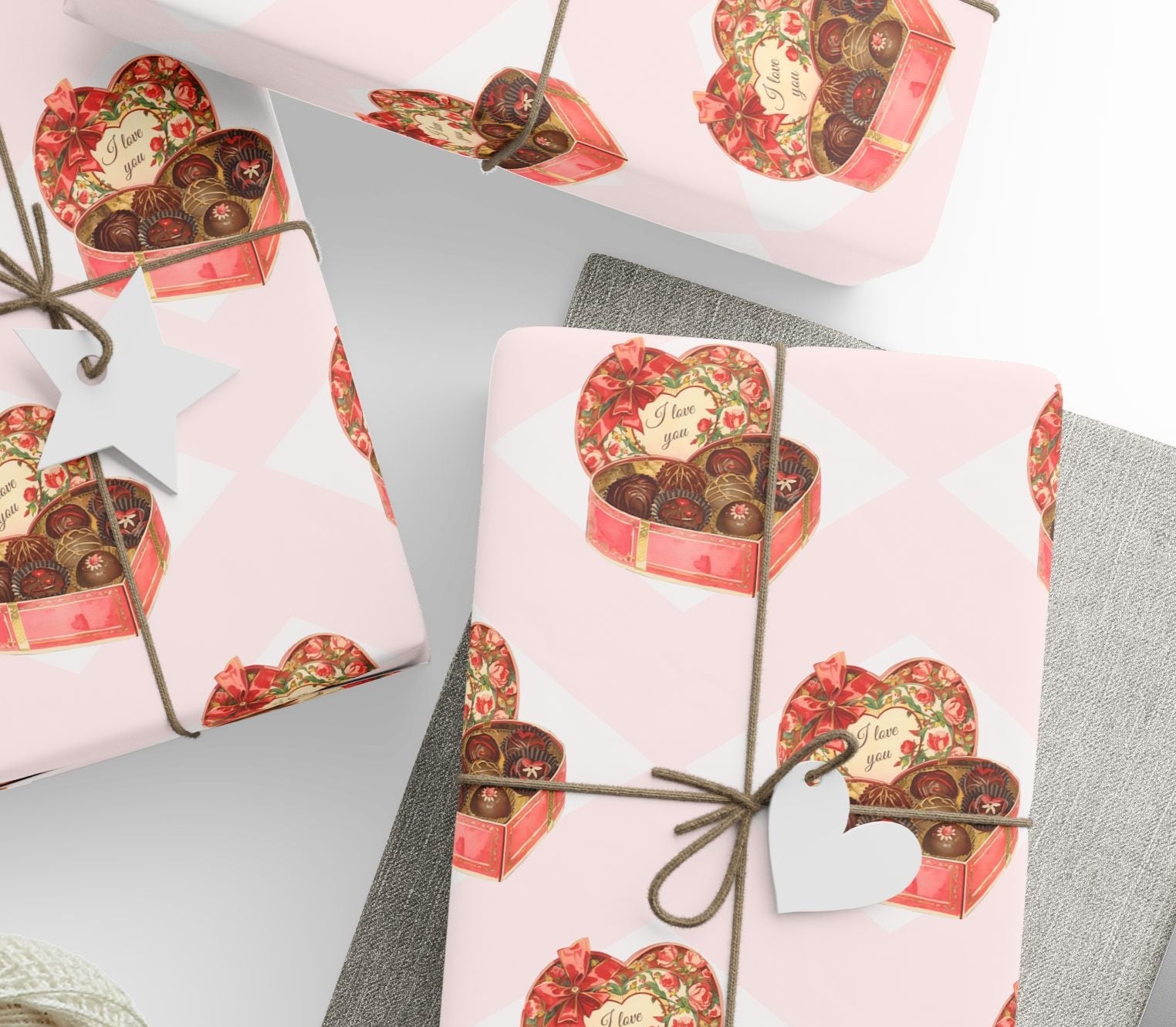 Vintage valentine chocolate box wrapping paper with heart shaped candy boxes on blush background.