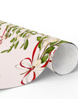 Vintage mistletoe wrapping paper with green leaves and red bows on blush background