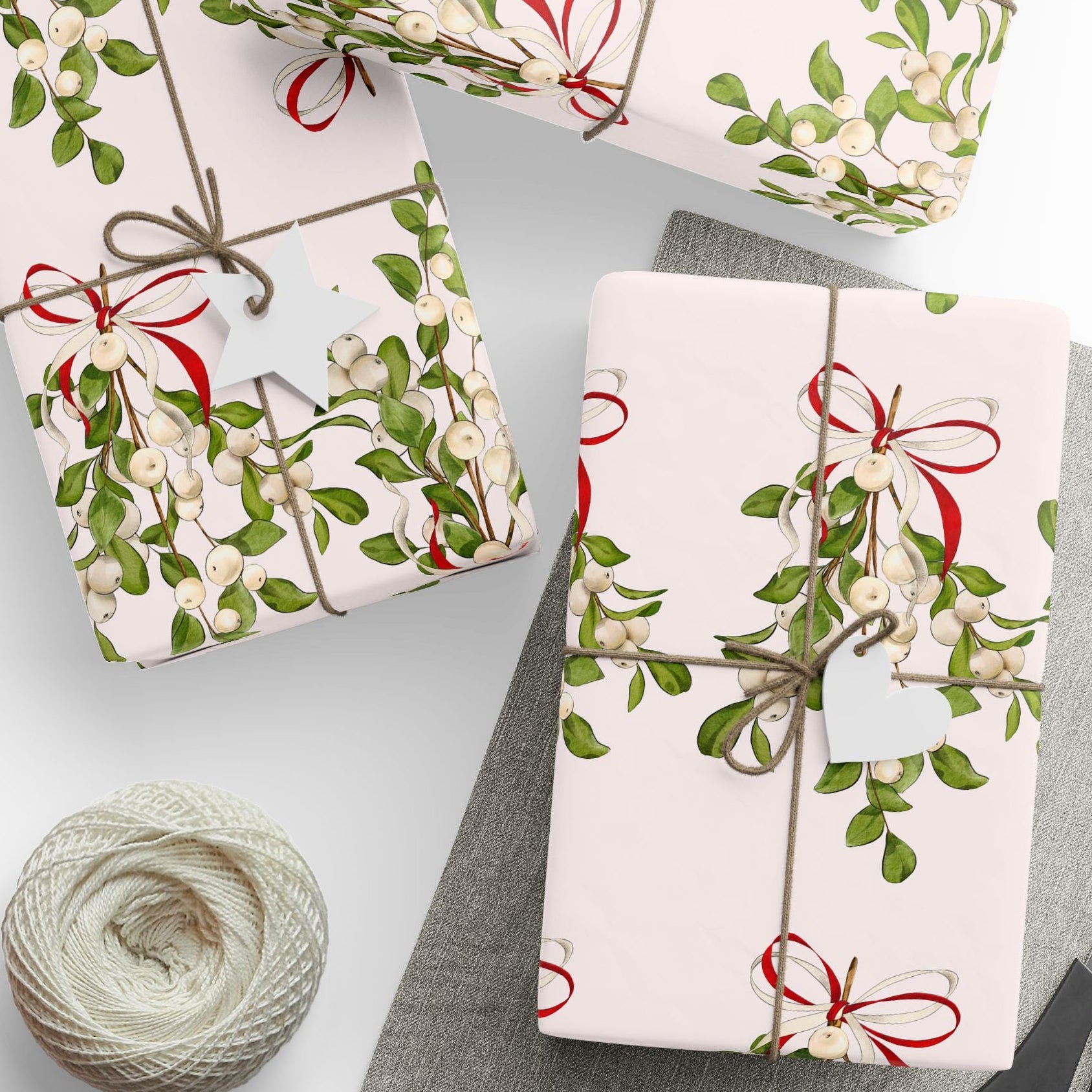 Vintage mistletoe wrapping paper with green leaves and red bows on blush background