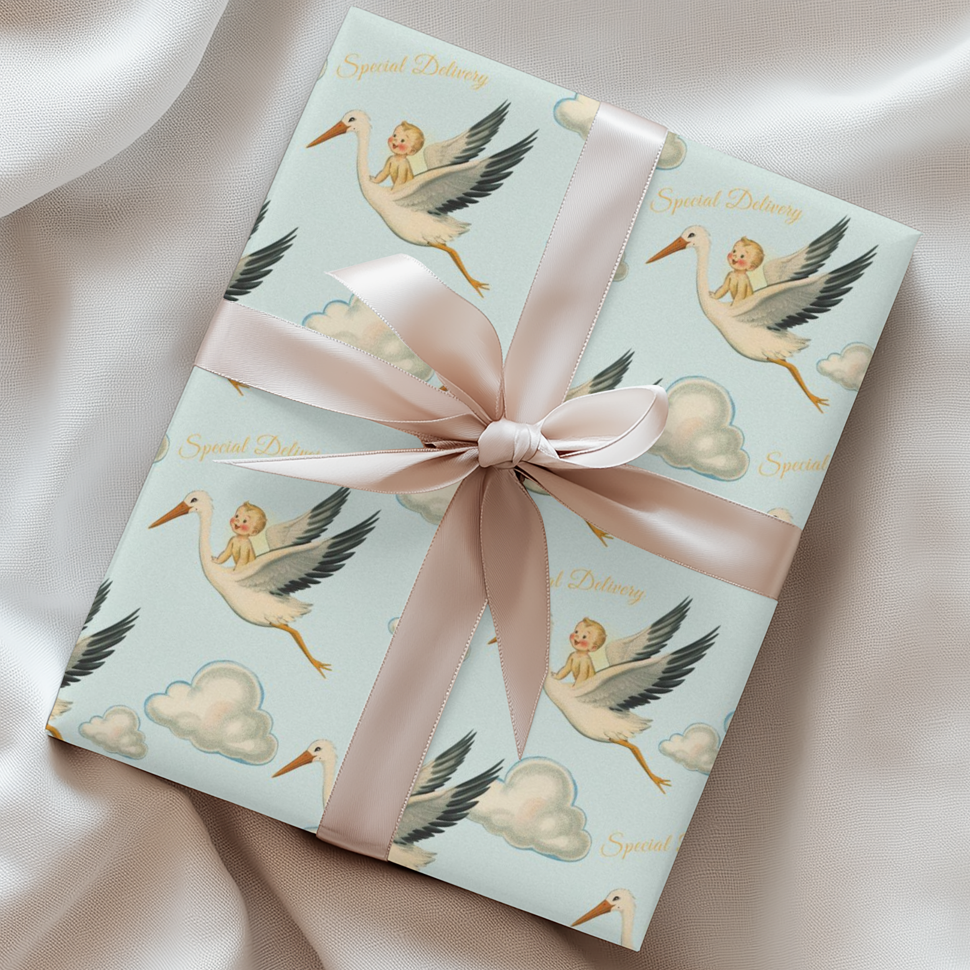 Gift box with stork design and pink ribbon on a satin surface