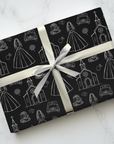 Wedding gift wrapped in black patterned paper with a white ribbon on a light gray background.