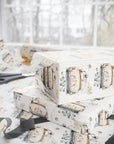 Side view of a gift box wrapped in ivory and blush Just Married car paper, showing the clean folds and repeating vintage car pattern.