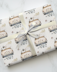A gift box wrapped in Just Married getaway car wedding paper, tied with a silver satin ribbon on a white marble surface.