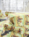 Stack of wrapped presents with cowgirl themed wrapping paper on a table.