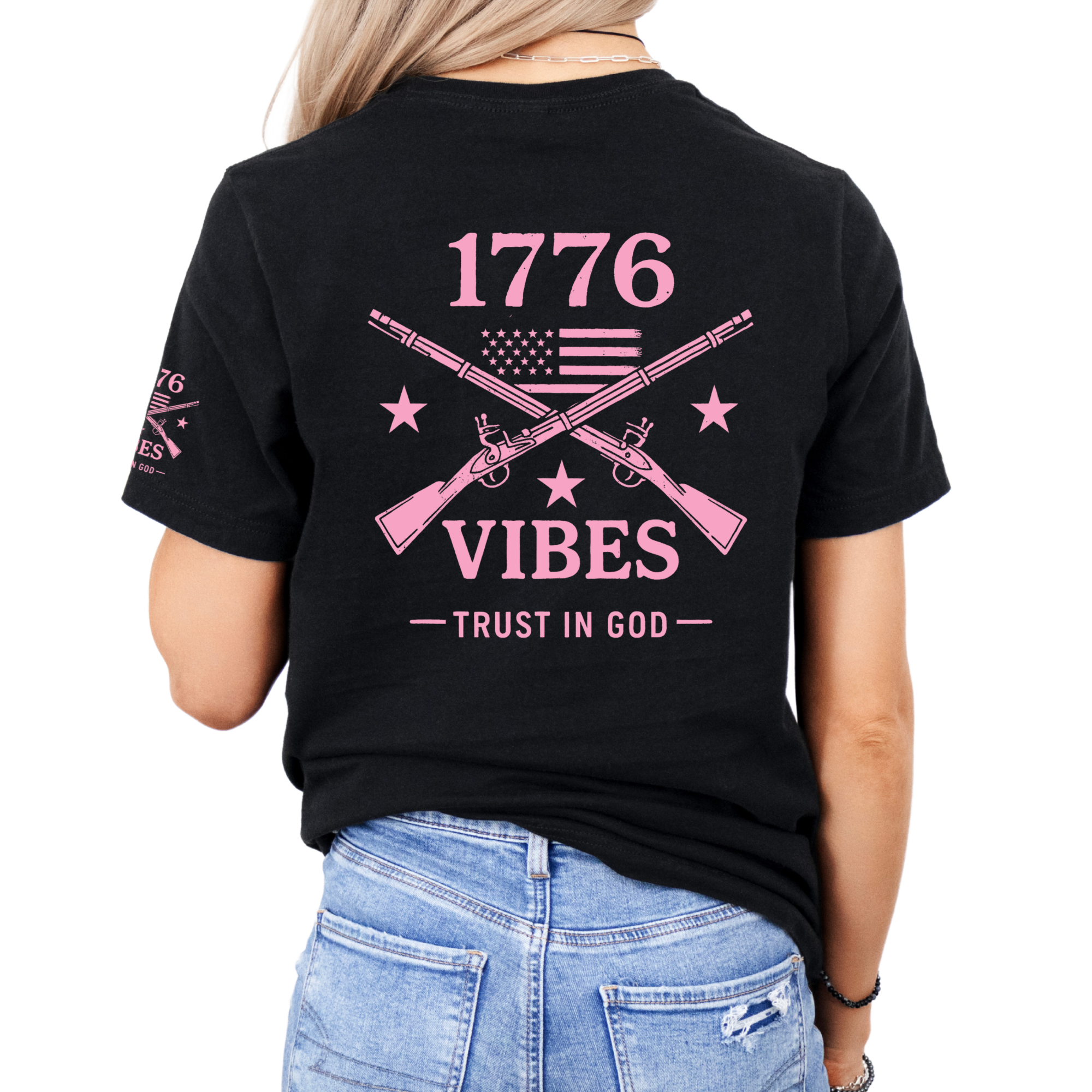 Black t-shirt with pink graphic that includes crossed muskets american flag and stars with text on the back, that says 1776 vibes trust in god
