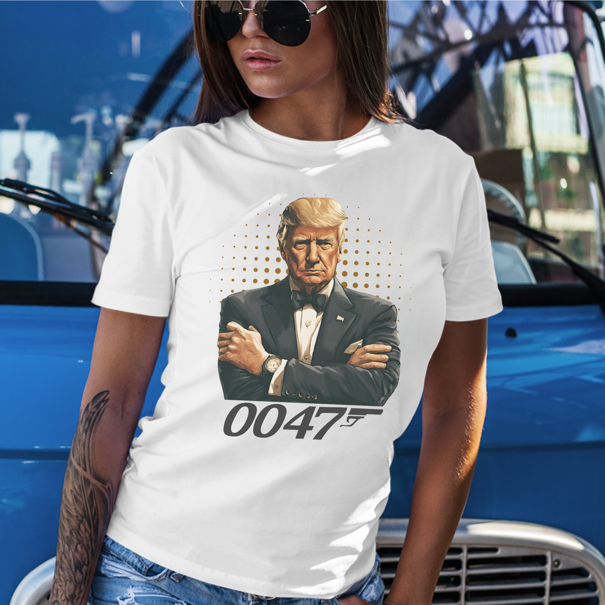 Woman wearing a white t-shirt with a graphic of the President of the United States in a tux and '0047' text posing against a blue truck