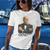 Woman wearing a white t-shirt with a graphic of the President of the United States in a tux and '0047' text posing against a blue truck