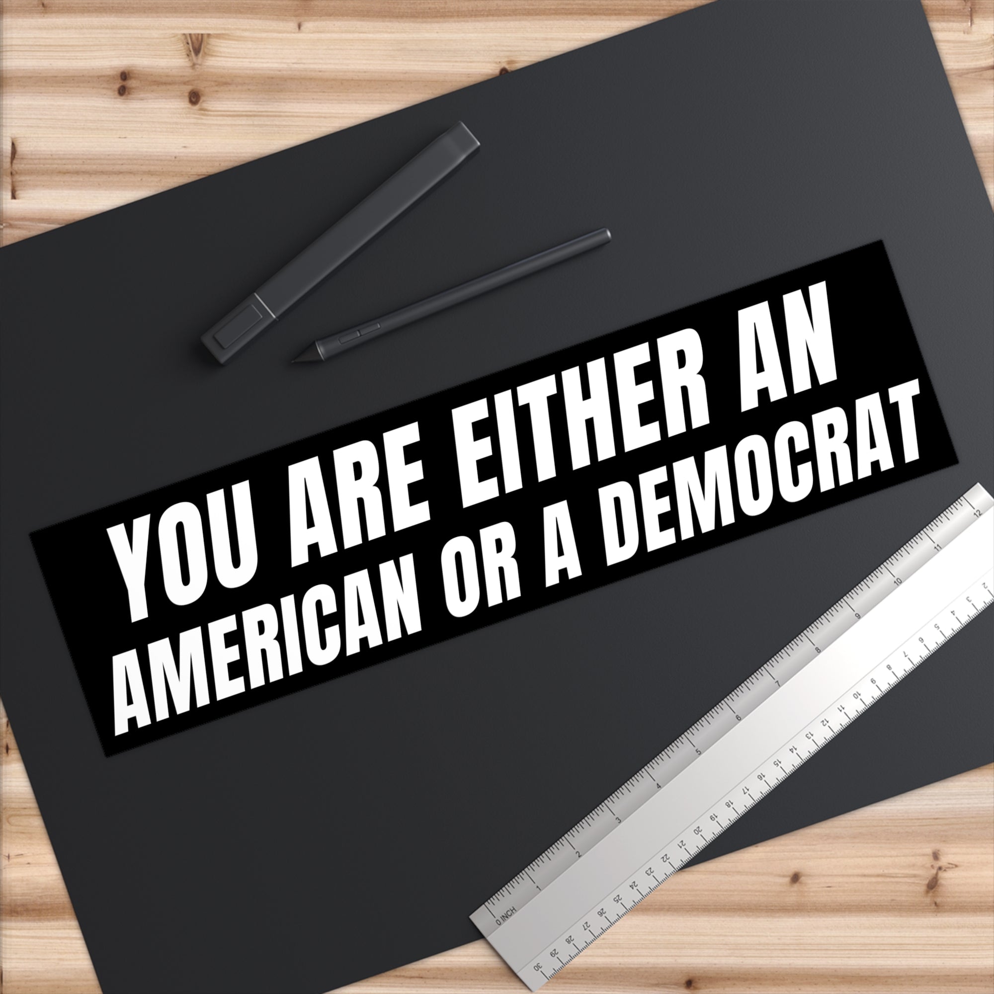 Bumper sticker with political text on a black surface with stationery items